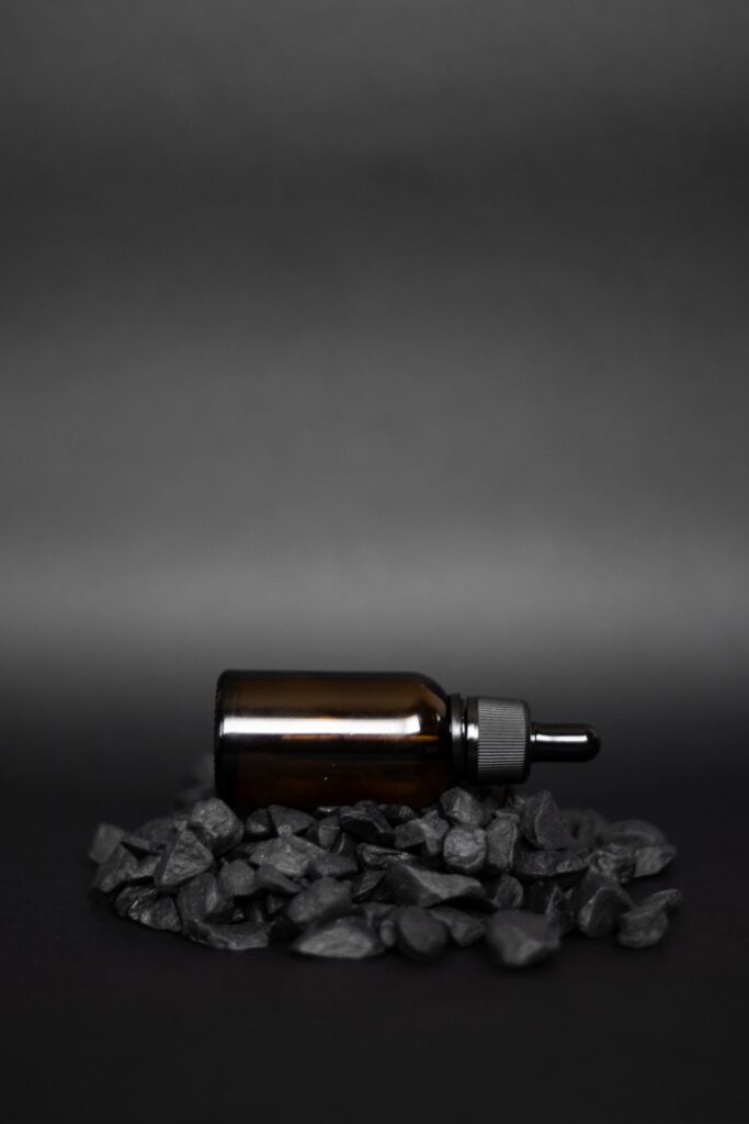 Flacon compte-gouttes ambré posé sur des pierres noires