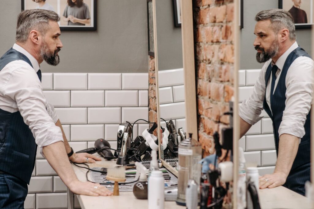 Homme barbu devant le miroir d’un barbershop