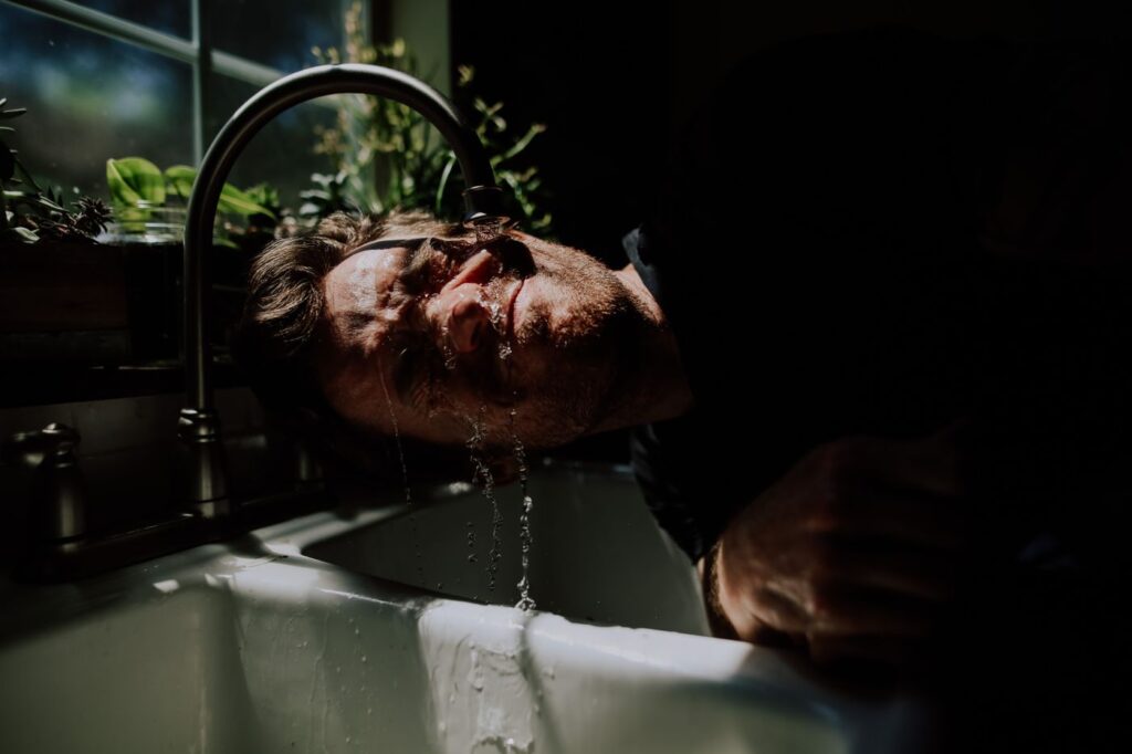 Homme barbu se rinçant le visage à l’eau